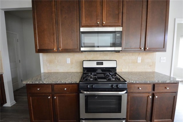 kitchen with dark brown cabinetry, light stone countertops, backsplash, and stainless steel appliances