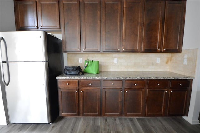 kitchen with backsplash, freestanding refrigerator, light wood-style floors, and light stone countertops