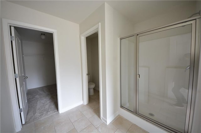 full bath featuring a spacious closet, a stall shower, toilet, and baseboards