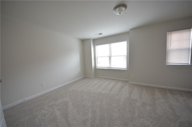 unfurnished room with visible vents, light carpet, and baseboards