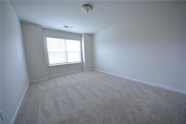 carpeted spare room featuring visible vents and baseboards