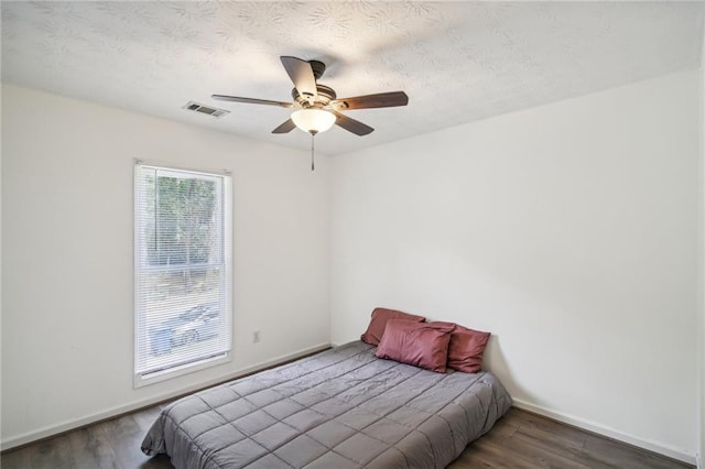 bedroom featuring a textured ceiling, ceiling fan, and dark hardwood / wood-style flooring