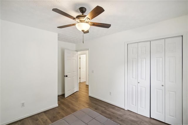 unfurnished bedroom featuring ceiling fan, dark hardwood / wood-style floors, and a closet