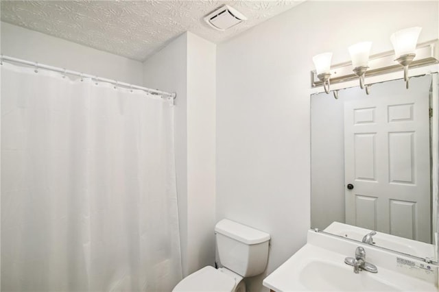 bathroom featuring toilet, a textured ceiling, and vanity