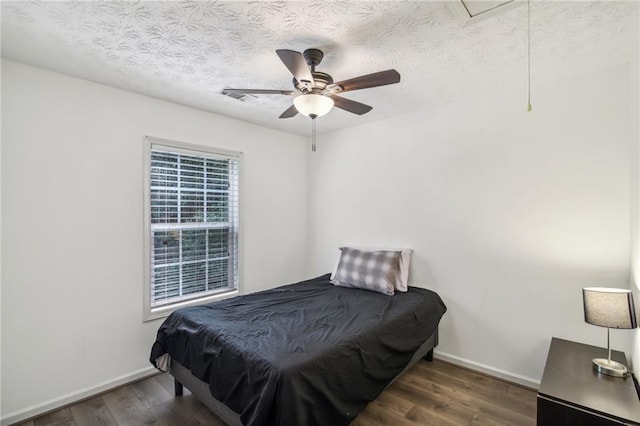 bedroom featuring ceiling fan, dark hardwood / wood-style floors, a textured ceiling, and multiple windows