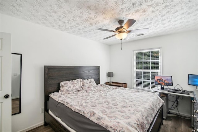 bedroom featuring ceiling fan, dark wood-type flooring, and a textured ceiling