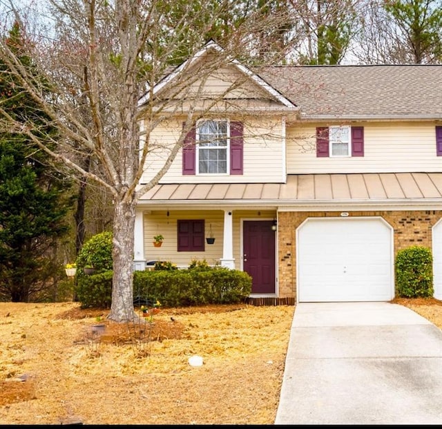 view of front of home with a standing seam roof, a porch, concrete driveway, metal roof, and brick siding