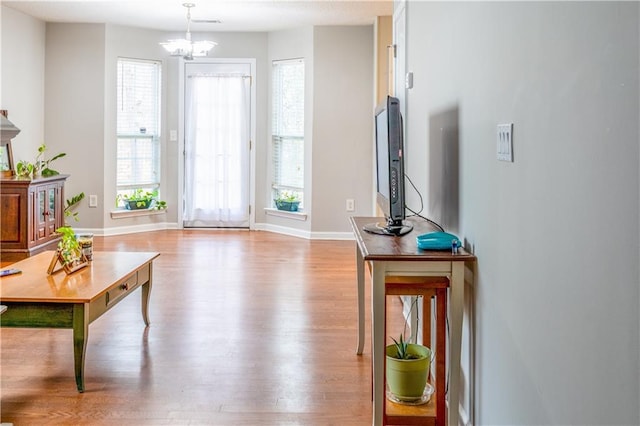 interior space featuring a notable chandelier, wood finished floors, and baseboards