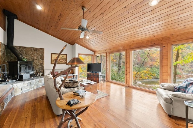 living room featuring wood ceiling, lofted ceiling, light hardwood / wood-style flooring, and a wood stove