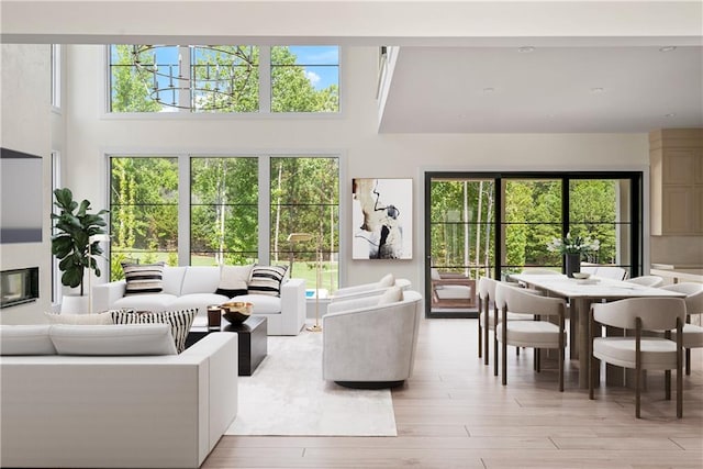 living room with light wood-type flooring, plenty of natural light, and a high ceiling