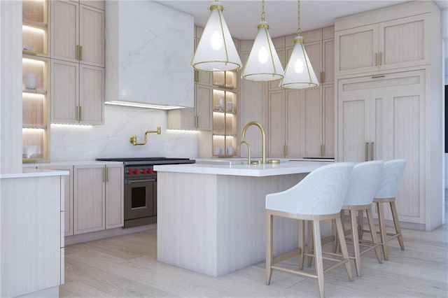 kitchen with custom range hood, light hardwood / wood-style flooring, decorative backsplash, an island with sink, and premium stove