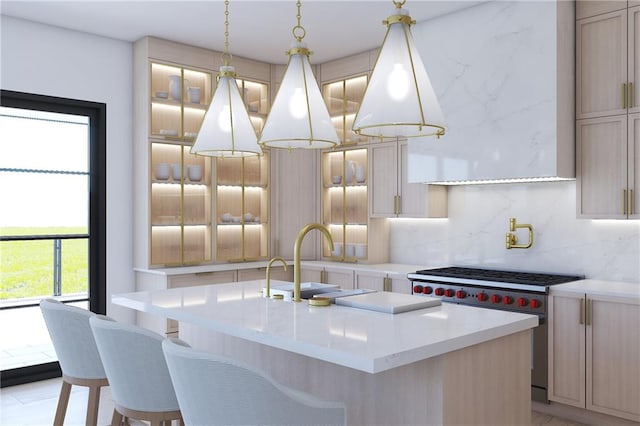 kitchen featuring decorative backsplash, sink, an island with sink, light brown cabinets, and designer stove