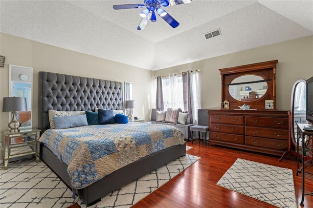 bedroom featuring ceiling fan, wood-type flooring, vaulted ceiling, and a textured ceiling