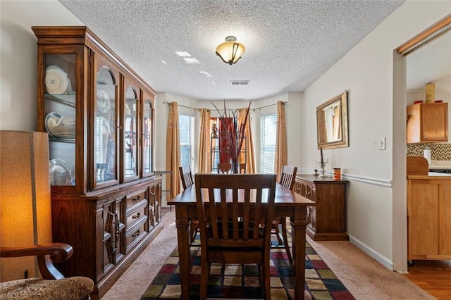 dining area featuring dark carpet and a textured ceiling