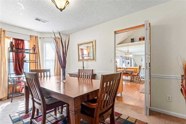 dining area featuring light colored carpet and a textured ceiling