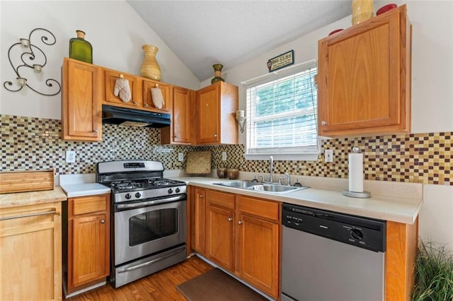 kitchen featuring lofted ceiling, sink, backsplash, stainless steel appliances, and light wood-type flooring