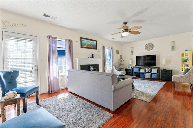 living room with ceiling fan, a textured ceiling, and dark hardwood / wood-style flooring