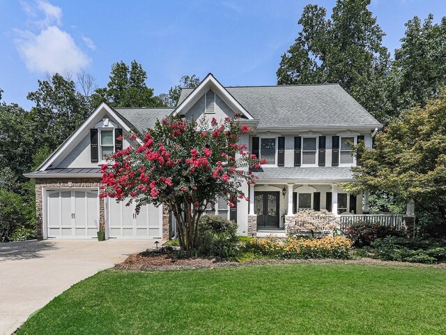 view of front facade featuring a garage, a front lawn, and a porch