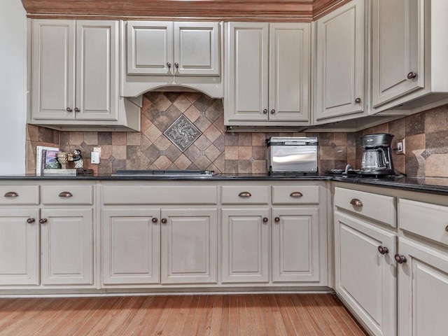 kitchen with light wood-type flooring, black stovetop, and white cabinets