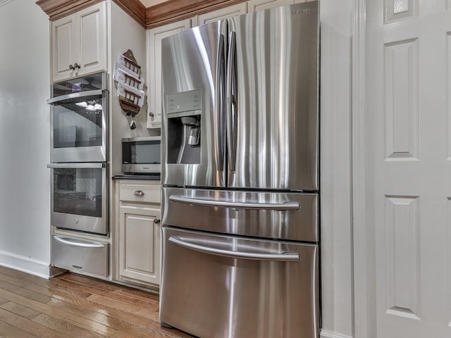 kitchen featuring baseboards, white cabinets, light wood-style flooring, appliances with stainless steel finishes, and a warming drawer