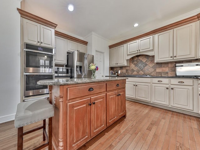 kitchen with tasteful backsplash, a kitchen island, appliances with stainless steel finishes, crown molding, and light wood-style floors