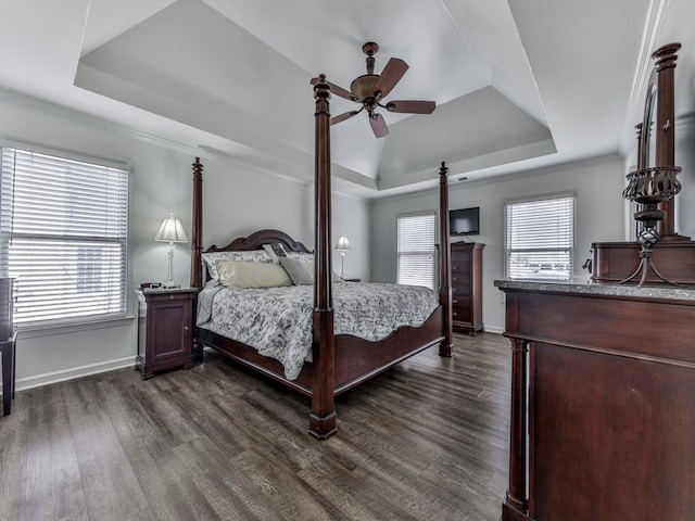 bedroom with a ceiling fan, a raised ceiling, dark wood finished floors, and baseboards