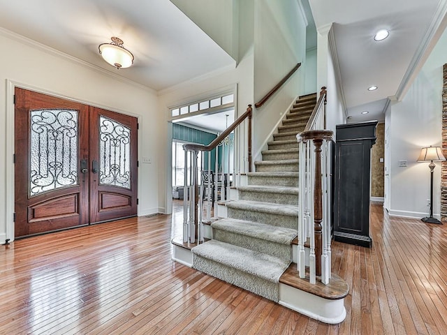 entryway with ornamental molding, stairway, baseboards, and wood finished floors