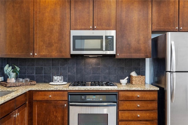 kitchen featuring decorative backsplash, light stone countertops, and appliances with stainless steel finishes