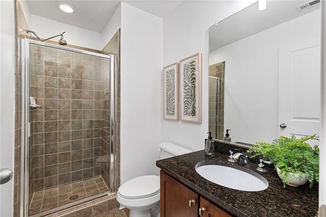 bathroom with visible vents, toilet, a stall shower, and vanity