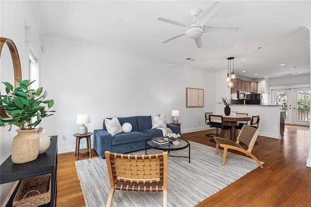 living room with ceiling fan, baseboards, and wood finished floors