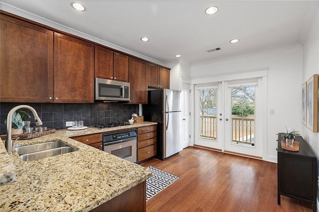 kitchen with a sink, ornamental molding, appliances with stainless steel finishes, french doors, and dark wood-style flooring