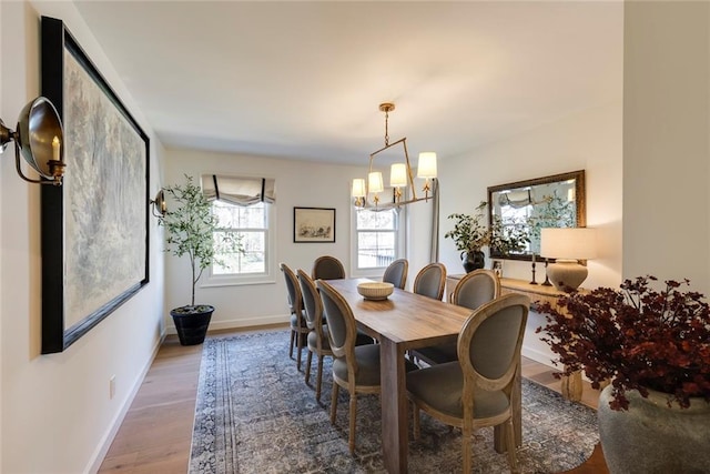 dining space with an inviting chandelier, baseboards, and wood finished floors