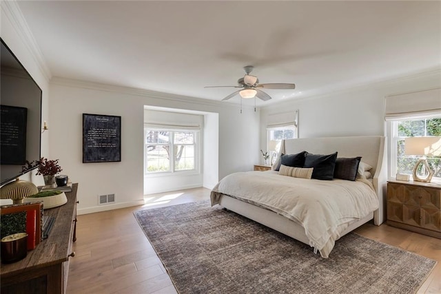 bedroom with baseboards, light wood-type flooring, visible vents, and crown molding