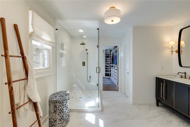 full bath featuring marble finish floor, a spacious closet, a stall shower, vanity, and baseboards