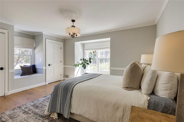 bedroom with ornamental molding, multiple windows, wood finished floors, and visible vents