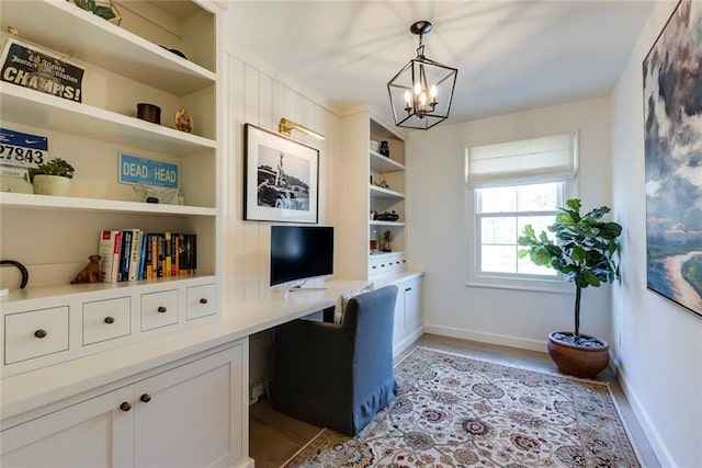 office space with built in shelves, built in study area, light wood-style flooring, and baseboards