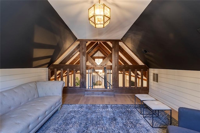 interior space featuring visible vents, vaulted ceiling, wood walls, and wood finished floors