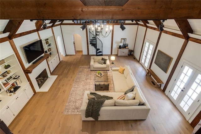 living area featuring stairs, arched walkways, wood finished floors, and a wealth of natural light