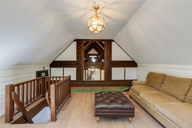 additional living space featuring vaulted ceiling, wood walls, wood finished floors, and an inviting chandelier