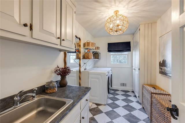 laundry room with cabinet space, visible vents, washing machine and clothes dryer, light floors, and a sink