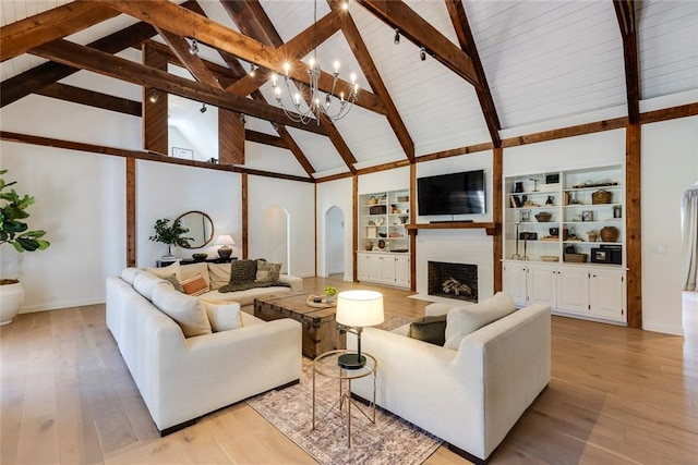 living room with arched walkways, a large fireplace, baseboards, light wood-type flooring, and beam ceiling