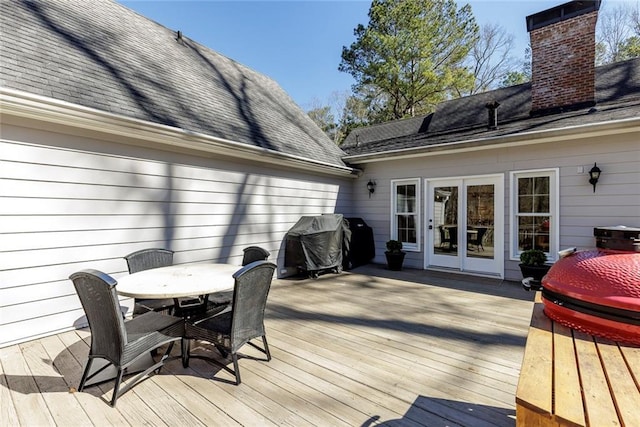 wooden terrace featuring outdoor dining area and a grill