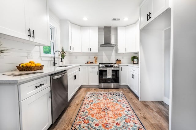 661 Inglewood Dr SE, Smyrna, GA 30080 - kitchen with wall chimney range hood, appliances with stainless steel finishes, a sink, light wood-style flooring, and light countertops