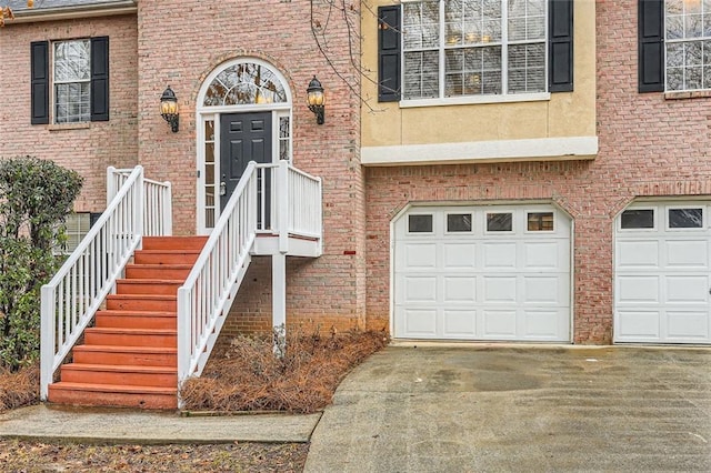 doorway to property with driveway, brick siding, and an attached garage