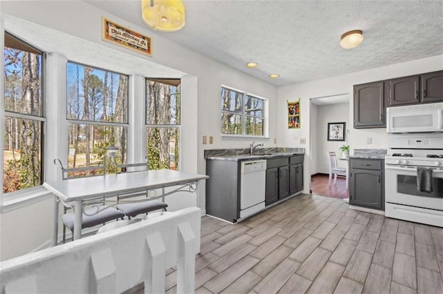 kitchen with white appliances, light wood-style flooring, a sink, a textured ceiling, and recessed lighting