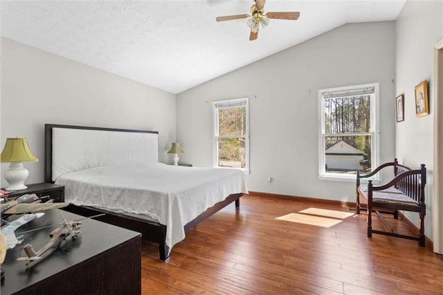 bedroom with vaulted ceiling, hardwood / wood-style flooring, baseboards, and ceiling fan