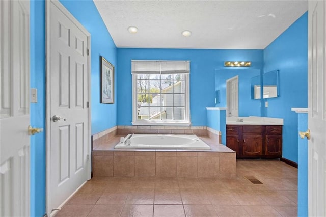 bathroom featuring a garden tub, tile patterned flooring, vanity, and a textured ceiling