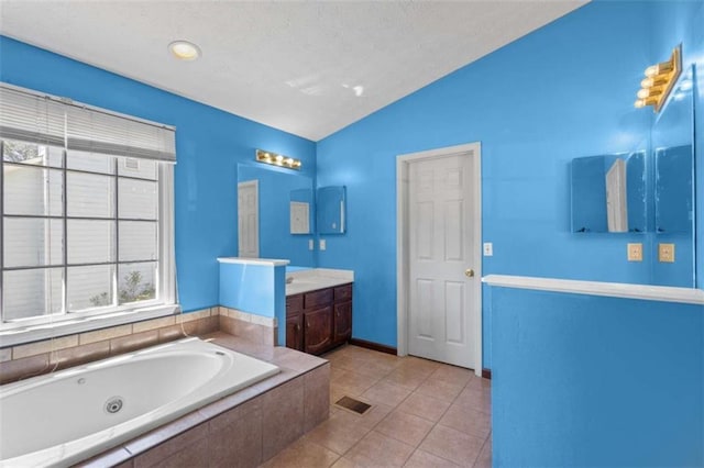 bathroom featuring lofted ceiling, a whirlpool tub, vanity, baseboards, and tile patterned floors