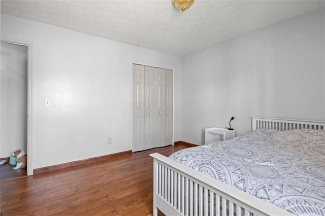 bedroom with hardwood / wood-style flooring, a textured ceiling, a closet, and baseboards