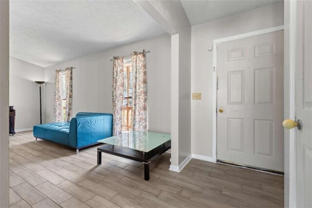 entryway featuring wood finished floors, baseboards, and a textured ceiling